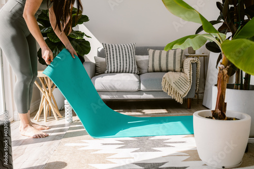 Woman placing yoga mat in apartment