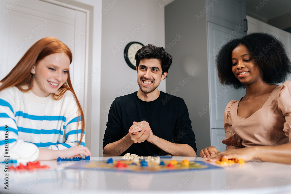 Portrait of cheerful young man throwing dice playing in board game with multiethnic friends, enjoying pastime leisure activity at home. Diverse happy people having fun and enjoying competition. Portrait of cheerful young man throwing dice playing in board game with multiethnic friends, enjoying pastime leisure activity at home. Diverse happy people having fun and enjoying competition.