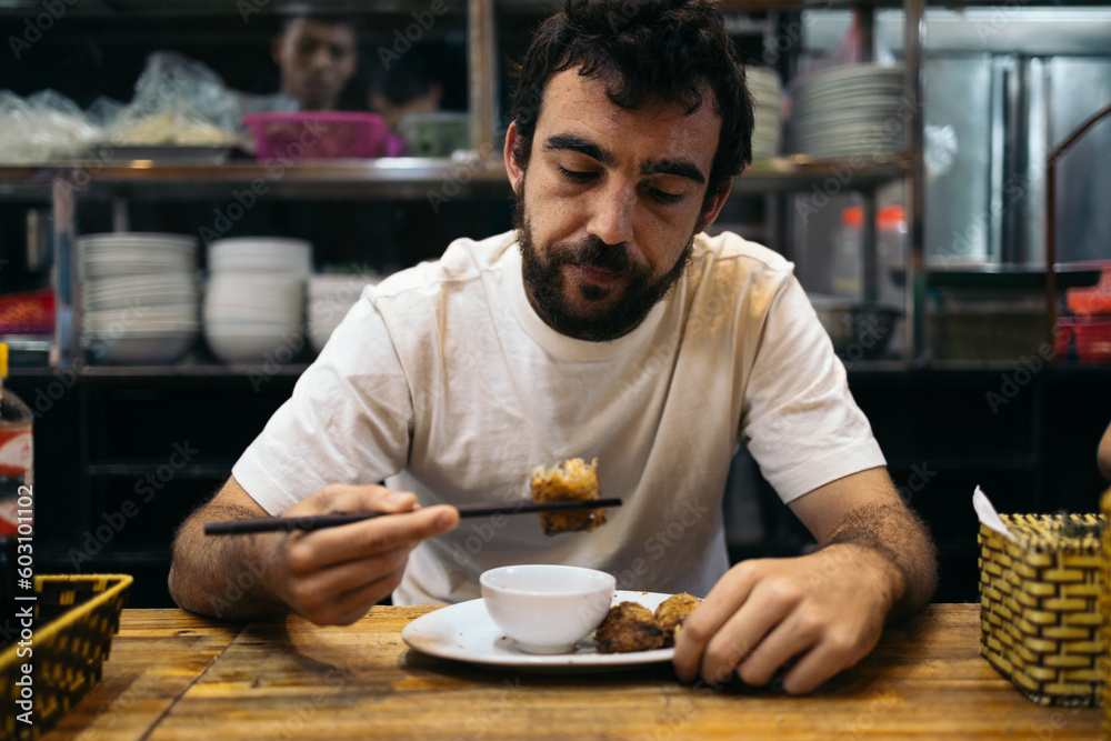 Caucasian man eating oriental food in Southeast Asia Caucasian man eating oriental food in Southeast Asia