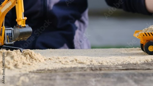 A child plays in the sand with a yellow excavator and a truck. Children's YouTube channel. Construction concept.