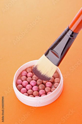 cosmetic brush and rouge on the orange background