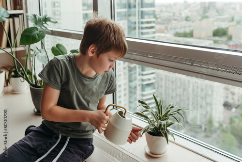 Kid takes care of green plants at modern home.