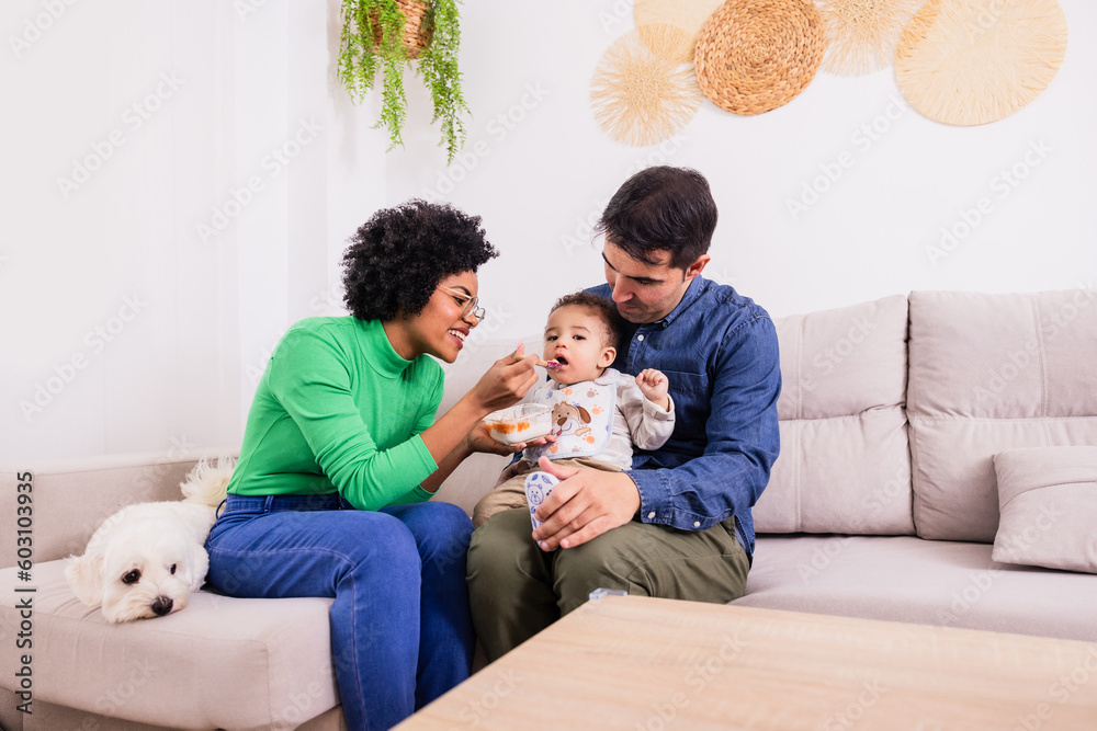 Cheerful black mother and father feeding little son with puree Cheerful black mother and father feeding little son with puree