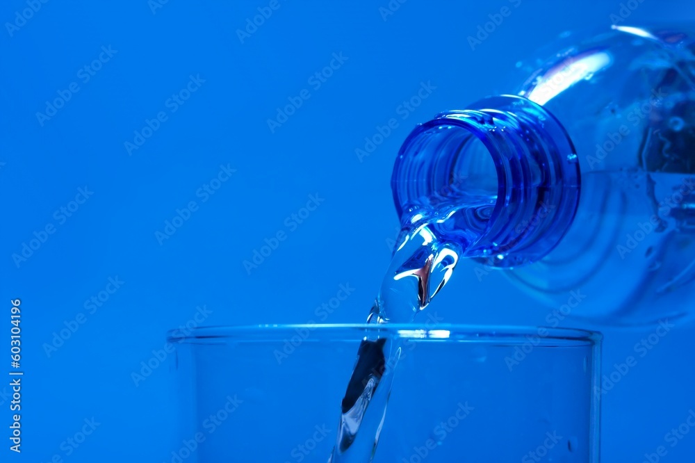 Pouring water from a bottle, blue background Pouring water from a bottle, blue background