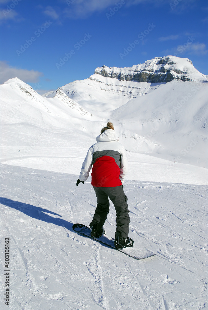 Girl snowboarding on the backdrop of scenic view in Canadian Rocky mountains ski resort Girl snowboarding on the backdrop of scenic view in Canadian Rocky mountains ski resort
