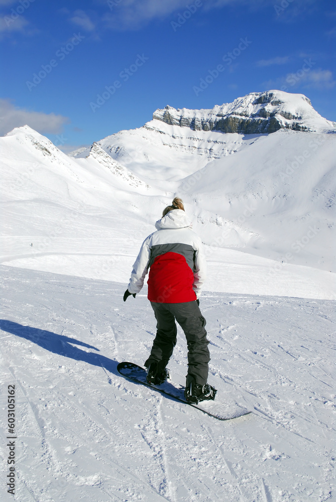 Girl snowboarding on the backdrop of scenic view in Canadian Rocky mountains ski resort