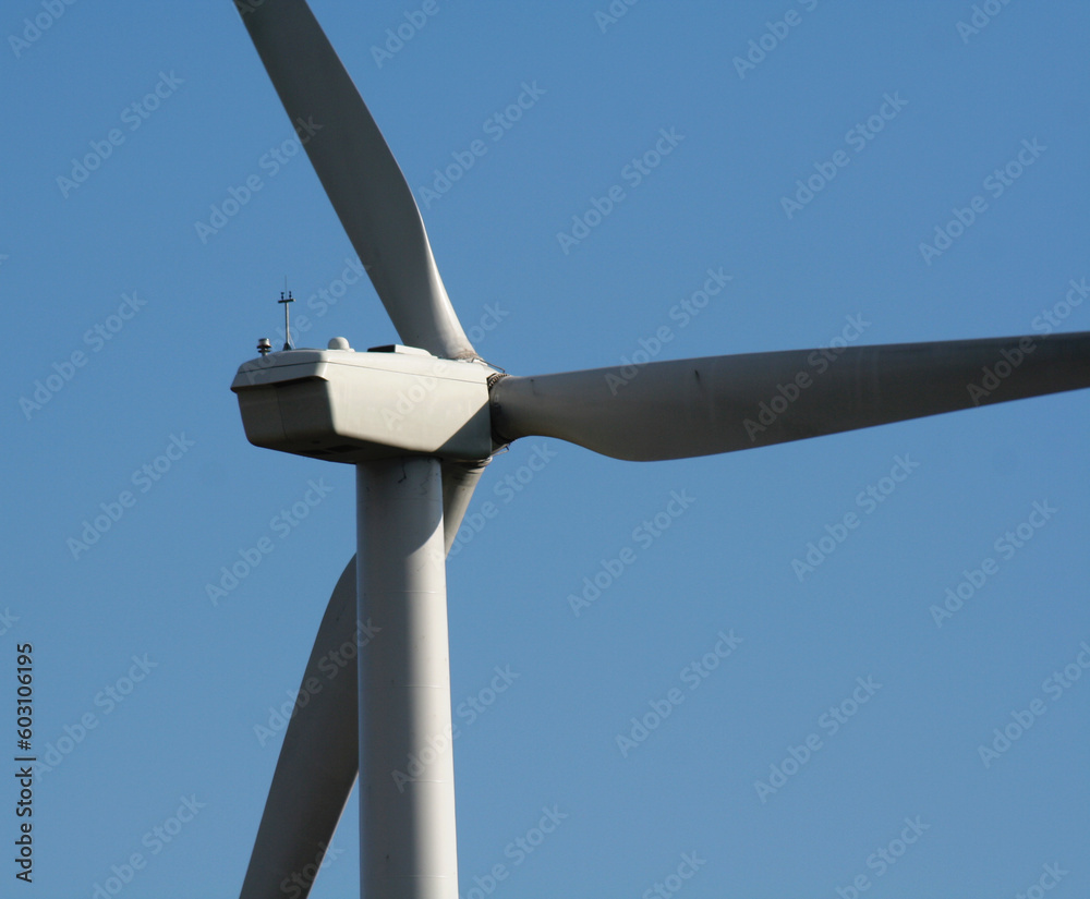 A close up of wind turbine shot from behind against the blue sky.