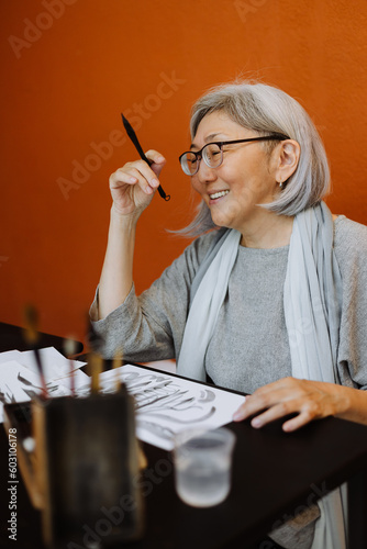 Elderly female calligrapher creating calligraphy works
