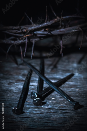 Crown thorns and nails as symbol of passion, death and resurrection of Jesus Christ. Selective focus on metal nails. Vertical image.