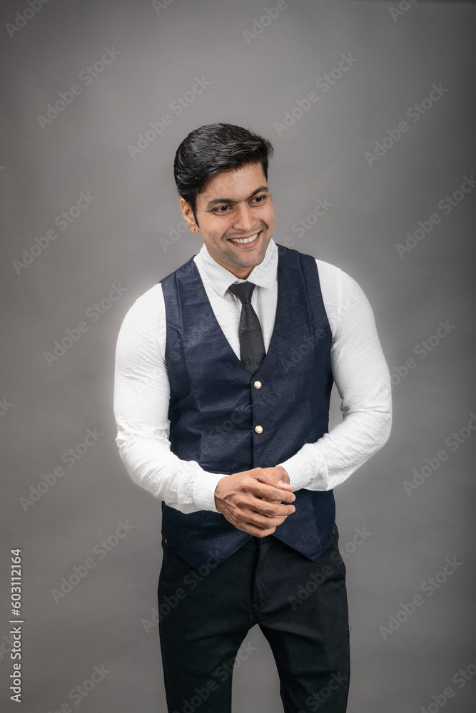 Studio shot of cheerful, young, handsome Indian business man in formal wear against grey background. Male model. Fashion Portrait. Studio shot of cheerful, young, handsome Indian business man in formal wear against grey background. Male model. Fashion Portrait.