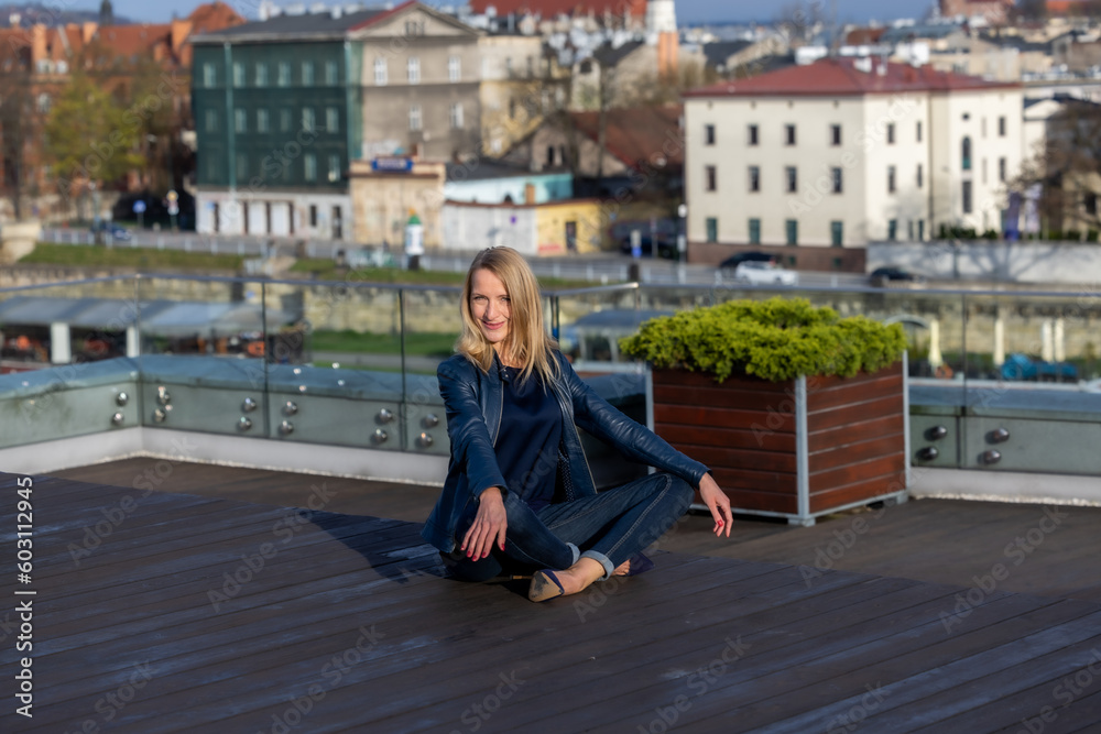 Beautiful woman in a blue jacket, dark shirt and blue jeans posing against the background of the city of Krakow