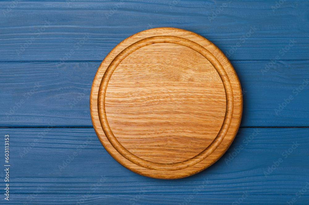 Cutting board over kitchen towel on blue kitchen table background. Recipe. Kitchenware. Empty modern wooden cutting board. Menu. MOCKUP. Place for text. Place to copy. Cutting board over kitchen towel on blue kitchen table background. Recipe. Kitchenware. Empty modern wooden cutting board. Menu. MOCKUP. Place for text. Place to copy.