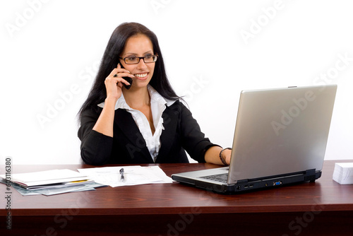 Young woman calls on cellphone over a laptop computer