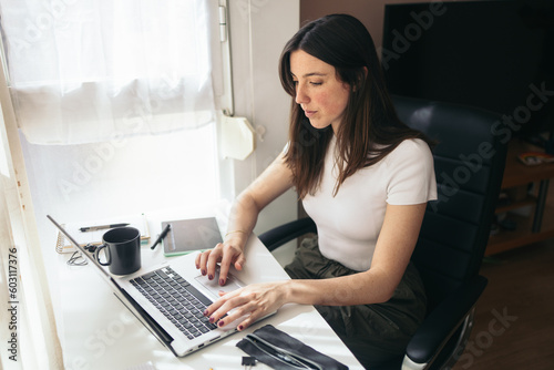 Home office: young woman teleworking with laptop at home