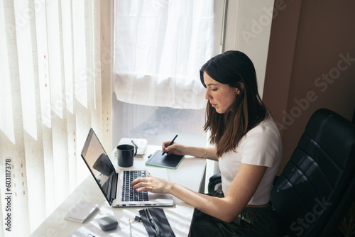 Home office: young woman teleworking with laptop at home photo