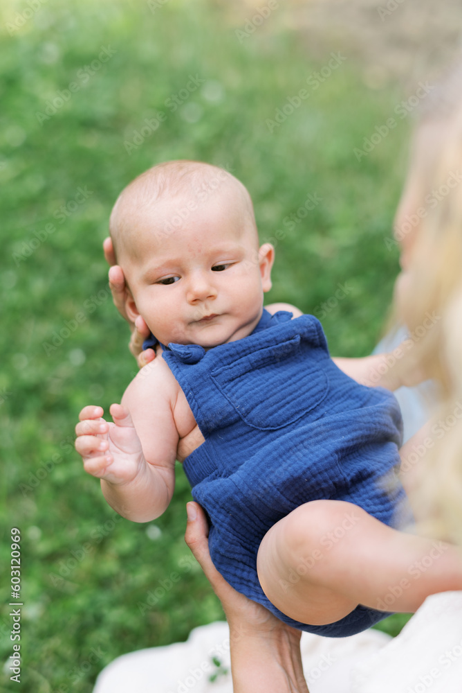 Smiling happy mother holding her baby in arms outdoors in summer Smiling happy mother holding her baby in arms outdoors in summer