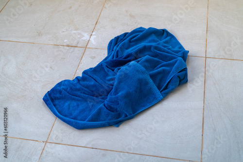 Dirty, used towel thrown on the tile floor at a hotel room