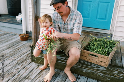 father sitting on porch with his daughter, doing farm chores together