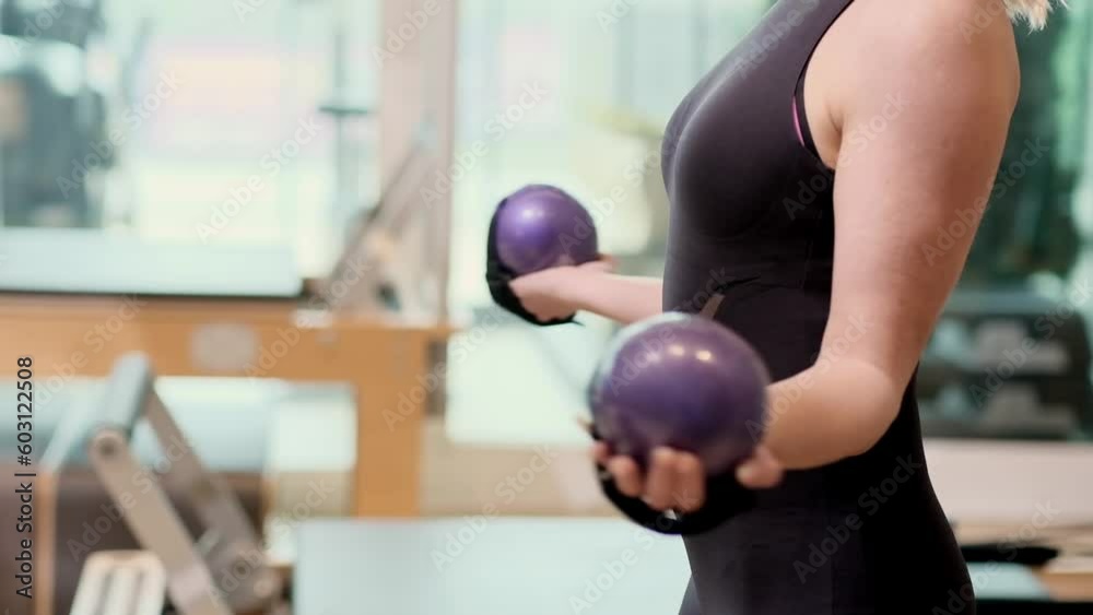 Active woman in sportswear doing pilates exercise with dumbbells in hands to strengthen muscles female person taking care of body and health training in gym Active woman in sportswear doing pilates exercise with dumbbells in hands to strengthen muscles female person taking care of body and health training in gym