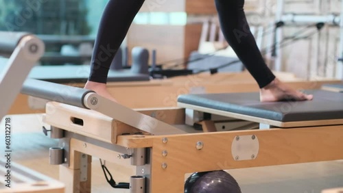 Effective pilates workout in gym professional coach doing stretching exercise for legs on modern reformer sportive woman enjoying training for flexible body photo