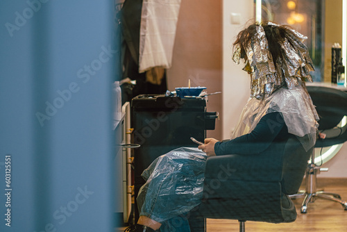 The person is waiting for her hair to be dyed in a beauty salon photo