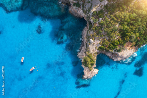 Top drone view of boats and yacths in transparent azure water at sunset. Aerial view of boats in clear blue sea  rocks  green forest. Travel in Sardinia  Italy. Tropical seascape. Nature. Sea bay
