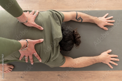 Unrecognizable coach supporting man doing Dolphin pose photo