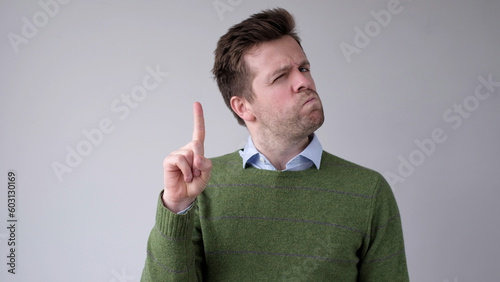 European young man shakes his head in disagreement and says no, pointing his finger upwards