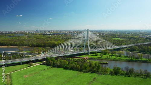 Cars drive on cable-stayed bridge under clear blue sky. Massive Redzinski Bridge over Oder river in sunny spring leading to Wroclaw aerial view photo