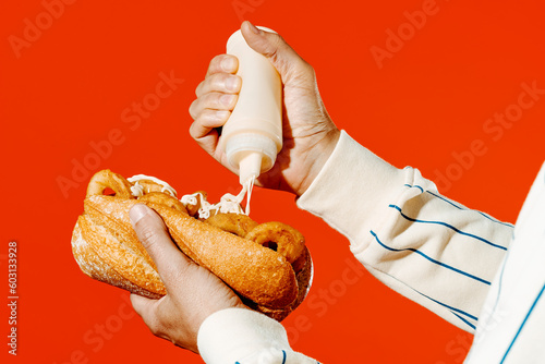 man puts some mayo in a spanish calamari sandwich