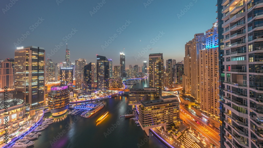 Aerial view to Dubai marina skyscrapers around canal with floating boats day to night timelapse