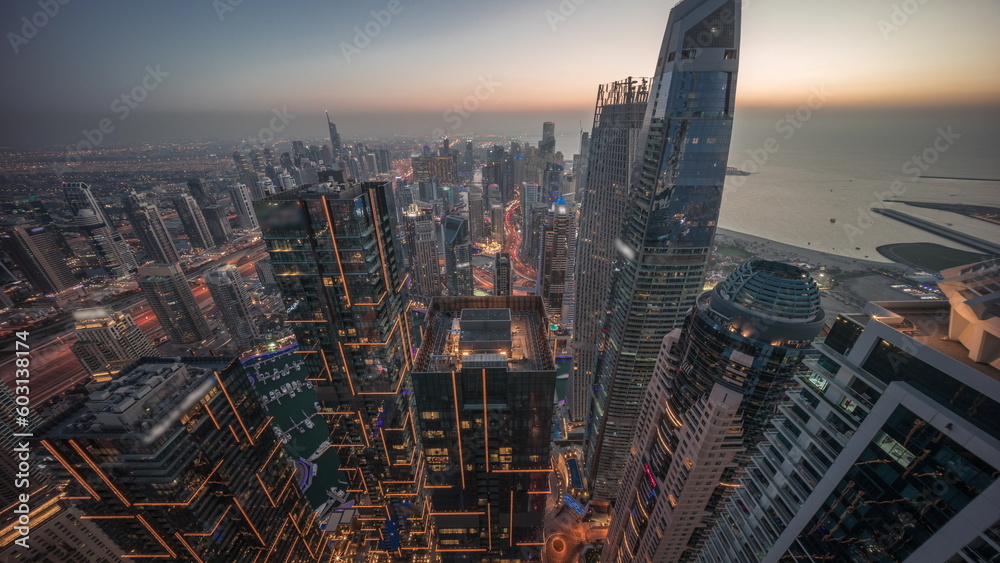 Obraz premium Skyline sunset view of Dubai Marina showing canal surrounded by skyscrapers along shoreline day to night timelapse. DUBAI, UAE