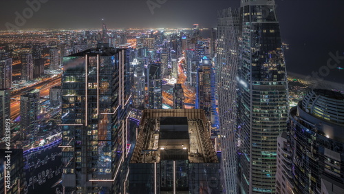 Panorama showing Dubai Marina and JLT district with traffic on highway between skyscrapers aerial night timelapse.