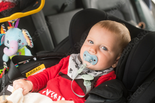 Baby with pacifier on car seat photo