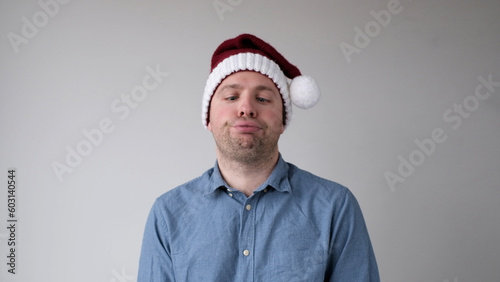 The sad and sorrowful European young man in a New Year's hat looks gloomily into the camera. Disappointments in the New Year celebration photo