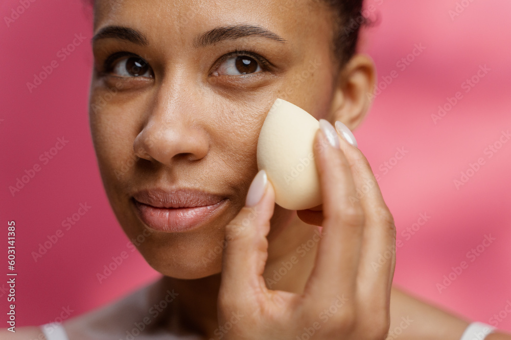 A woman uses a sponge while applying makeup A woman uses a sponge while applying makeup