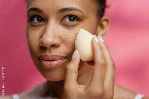A woman uses a sponge while applying makeup photo