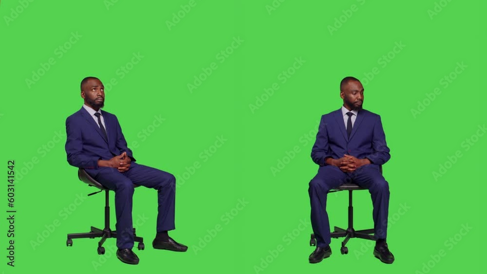 Male company entrepreneur sitting on chair in studio, wearing business suit and posing over full body green screen. Young office worker feeling confident on camera, corporate manager.