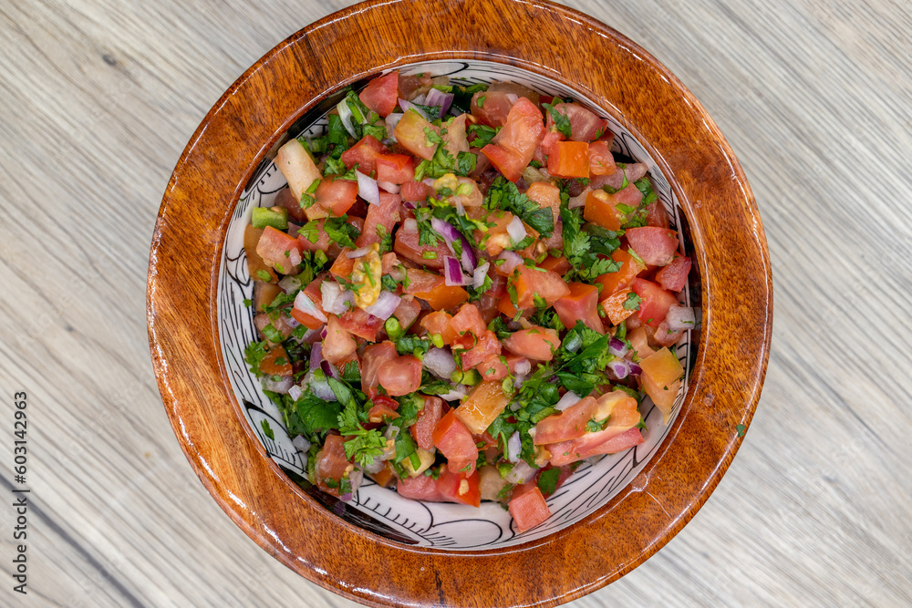 Overhead view of freshly made pico de gallo salsa served in a wooden bowl for a Mexican cuisine presentation