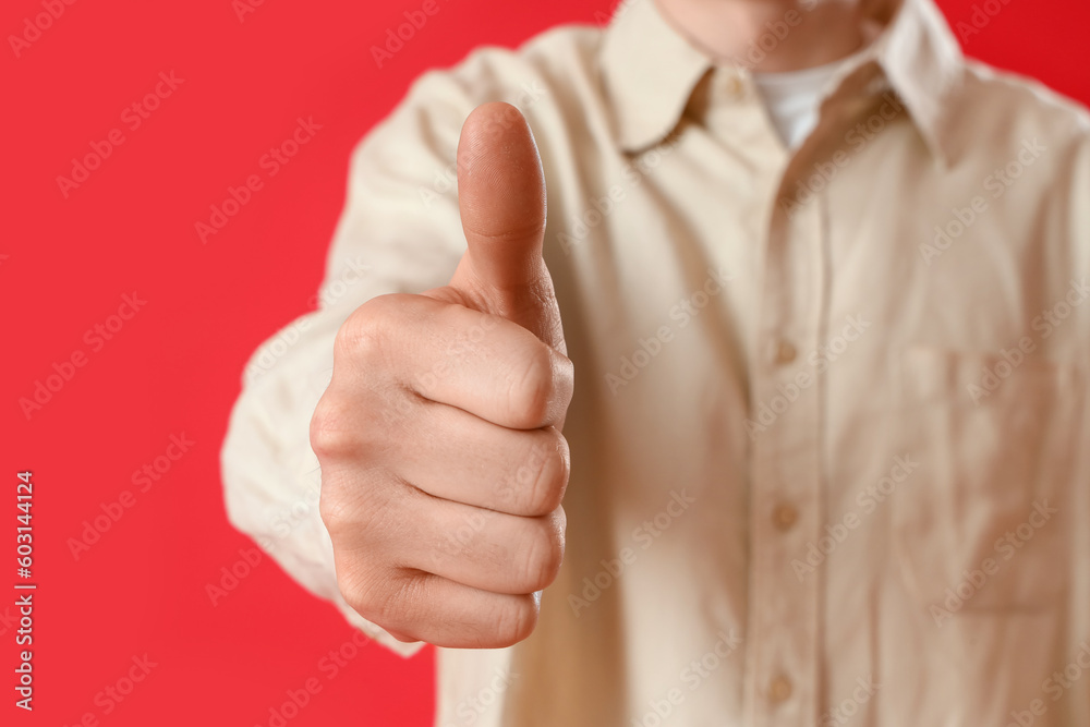 Young man showing thumb-up on red background Young man showing thumb-up on red background