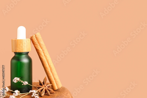 Bottle of essential oil, cinnamon stick, anise star and dried flowers on color background