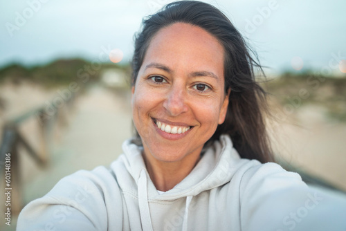 ugc selfie of tanned young woman on the beach at sunset photo