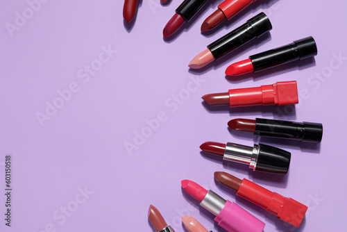 Frame made of different lipsticks on lilac background