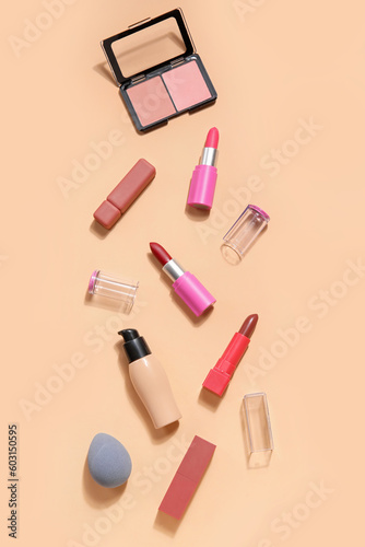 Decorative cosmetics with lipsticks and sponge on beige background