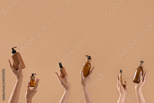 Hands holding many cosmetic products on beige background