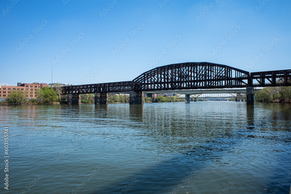 Railroad bridge across the Allegheny River in Pittsburgh, Pennsylvania, with other bridges in the background and a blue sky.