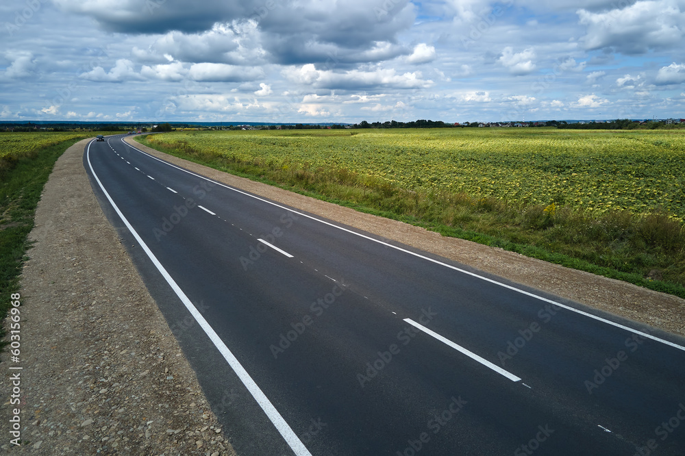 Aerial view of empty intercity road between green agricultural fields. Top view from drone of highway roadway