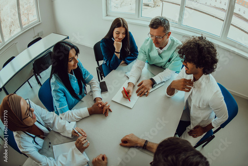 Top view of a group of multiethnic medical professionals including doctors, surgeons, and nurses are gathered in a hospital setting discussing patient care and using modern technology to address photo