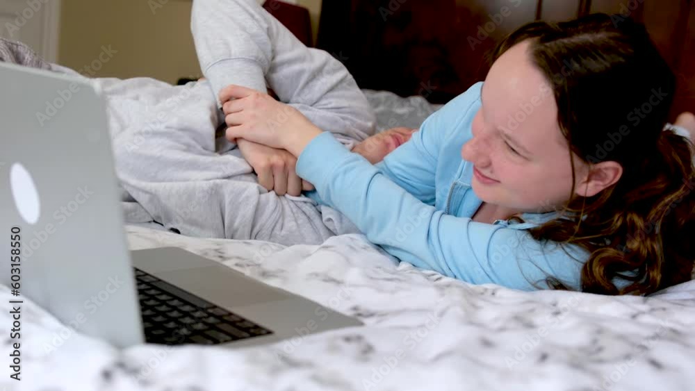 boys girl play wrestle hold each other's hands tickle not let go lie on bed teenagers near laptop choose program do not let other press button fun entertainment flirting fight break hands joke game