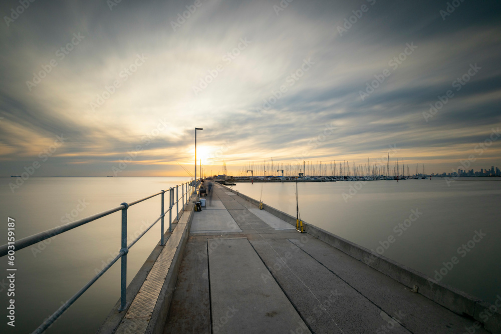 A jetty at sunset with a calm ocean